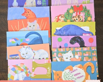 May include: A set of ten rectangular postcards featuring colorful illustrations of cats in various domestic settings, including sewing, crafting, and holiday scenes. Each card displays a unique cat character with distinct colors and artistic patterns.