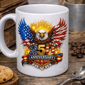 May include: White ceramic mug with a patriotic design. It features a bald eagle with wings in the colours of the American flag. The text "250 Anniversary 1776-2026" is displayed on a banner. The mug is suitable for hot beverages.