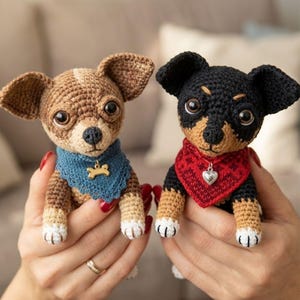 May include: Two crocheted Chihuahua dog figurines. One is brown and tan with a blue bandana and a bone charm. The other is black and tan with a red bandana and a heart charm. Both have large, expressive eyes and white paws.