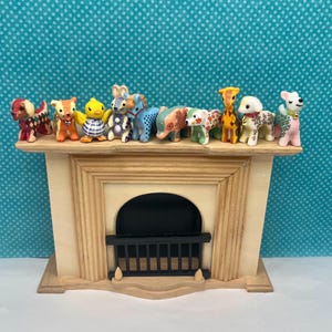May include: A decorative wooden fireplace mantel with a black firebox and a collection of small animal figurines. The figurines include dogs, a giraffe, an elephant, and a duck, each with unique patterns and colors.