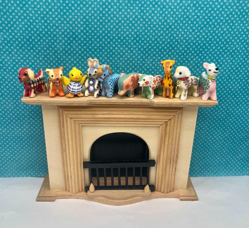 May include: A decorative wooden fireplace mantel with a black firebox and a collection of small animal figurines. The figurines include dogs, a giraffe, an elephant, and a duck, each with unique patterns and colors.