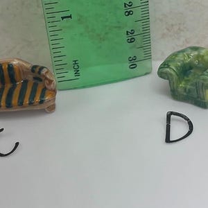 May include: Miniature furniture set including a striped sofa and a green armchair. The sofa is approximately 1 inch long. Also included are two black metal letter charms, a "C" and a "D".