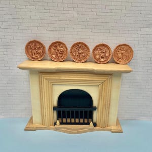 May include: Five small, round, brown decorative plates with relief carvings depicting scenes of people working. The plates are displayed on a cream-colored mantelpiece with a black grate and a white brick background. The plates are likely part of a decorative set.