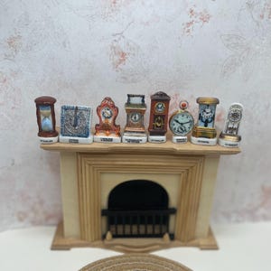 May include: A collection of miniature ceramic clocks in various shapes and colors, including an hourglass, a square clock, and a round pocket watch. The clocks are displayed on a miniature fireplace mantel.