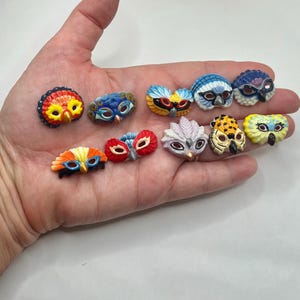 May include: A collection of colorful owl-shaped decorative pins. The pins feature various designs, including feathers, patterns, and different color combinations like red, yellow, blue, and orange. The pins are small and detailed.