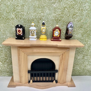 May include: Miniature fireplace mantel with five decorative clocks. The clocks are black, white, yellow, and brown. The mantel is made of light wood and has a black firebox.