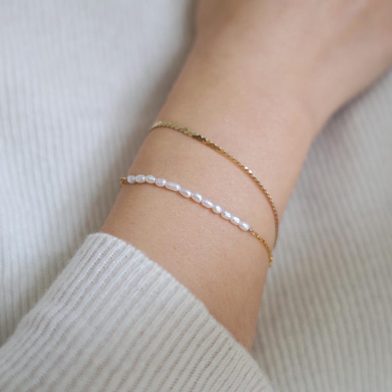 May include: A delicate gold chain bracelet with a single row of small white pearls.