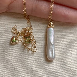 May include: A gold chain necklace with a large, white baroque pearl pendant.