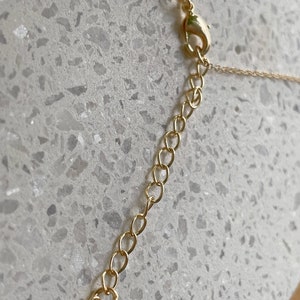 May include: A gold chain necklace with a heart-shaped clasp. The chain is made of small, linked circles.