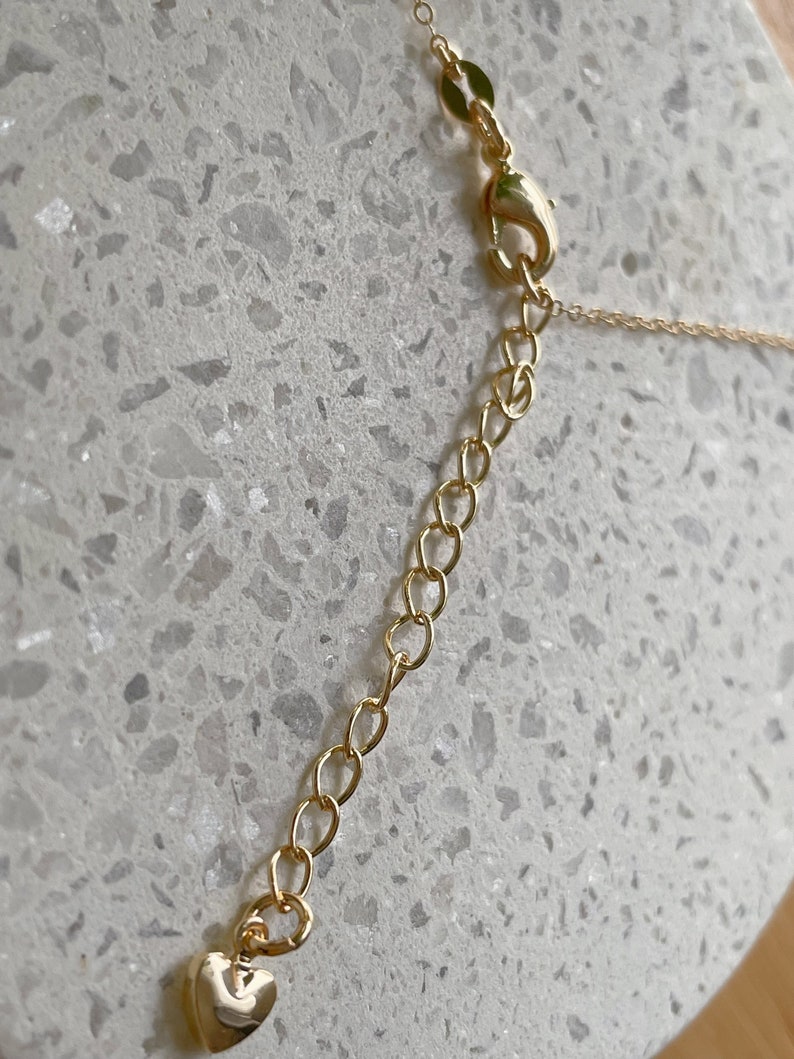 May include: A gold chain necklace with a heart-shaped clasp. The chain is made of small, linked circles.