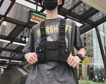 以下が含まれることがあります： 複数のポケットと調節可能なストラップが付いた黒い戦術的なチェストリグ。チェストリグは、「MRSH FF」という文字が印刷されたグレーのTシャツの上に着用されています。