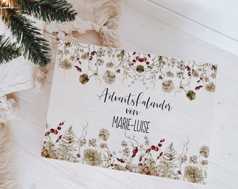 May include: A white advent calendar with a floral design and the text "Adventskalender von Marie-Luise". The calendar is sitting on a white wooden floor with a white fur rug and a wooden sled in the background.