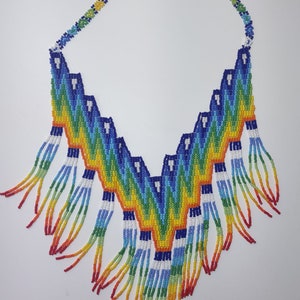 May include: A colorful beaded necklace with a rainbow fringe. The necklace is made of small, colorful beads and has a geometric pattern. The fringe is made of strands of beads in different colors.