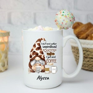 May include: White ceramic coffee mug with a brown and white gnome illustration. The mug has the text "I don't need another inspirational "QUOTE" I just need COFFEE" and the name "Alyssa" printed on it.