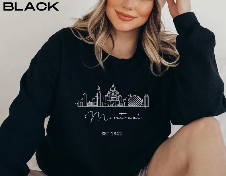 May include: Black sweatshirt with a white outline of the Montreal skyline and the text "Montreal EST 1642".