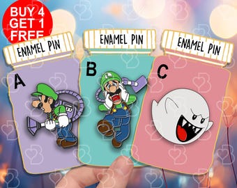 May include: Three enamel pins in the shape of pill bottles. The pins feature a green character with a vacuum cleaner, a green character with a scared expression, and a white ghost with a red mouth. The text "ENAMEL PIN" is printed on each bottle.