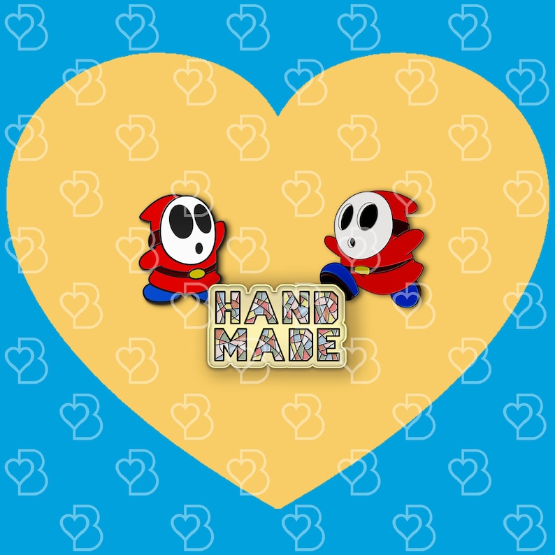 K&ouml;nnte beinhalten: Zwei rote und blaue Emaille-Pins mit einer Figur aus einem beliebten Videospiel. Die Pins befinden sich auf einem gelben herzf&ouml;rmigen Hintergrund mit einem Mosaik-Text 'HAND MADE' darunter.