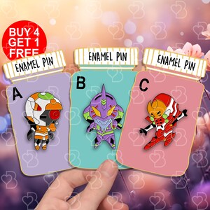 Könnte beinhalten: Drei Emaille-Pins mit verschiedenen Charakteren aus der Anime-Serie Neon Genesis Evangelion. Die Pins haben die Form einer Pillenflasche mit dem Aufdruck "Enamel Pin" auf der Oberseite. Die Charaktere sind Unit 01, Unit 00 und Unit 02. Die Pins befinden sich auf einem rosa, blauen und weißen Hintergrund.