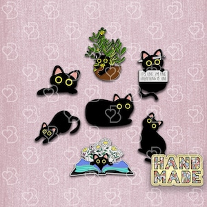 May include: A set of black cat enamel pins with various designs, including a cat in a pot plant, a cat reading a book, a cat with a sign that says "It's fine, I'm fine, everything is fine", and a cat with a flower crown. The pins are on a pink background with a "Handmade" sign.