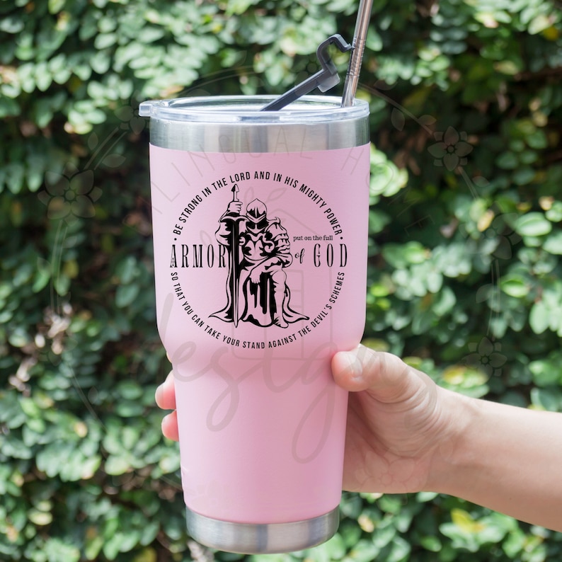 Puede incluir: Un vaso de acero inoxidable rosa con un gr&aacute;fico negro de un caballero con armadura. El gr&aacute;fico incluye el texto "Sean fuertes en el Se&ntilde;or y en su poder&iacute;o. P&oacute;nganse la armadura completa de Dios para que puedan resistir las estrategias del diablo."