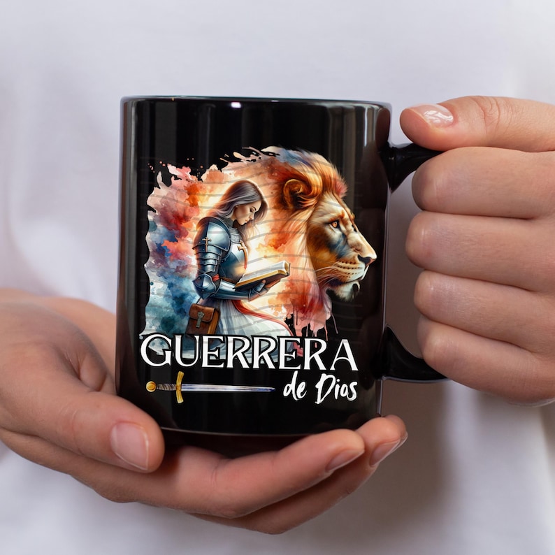 May include: Black ceramic mug with a colorful illustration of a woman in armor holding a book, a lion, and the text "GUERRERA de Dios".