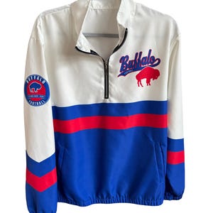 May include: White, blue, and red Buffalo Football jacket with a half-zip closure. The jacket features a Buffalo Bills logo patch on the left sleeve and the word "Buffalo" in script across the chest, along with a red bison graphic.