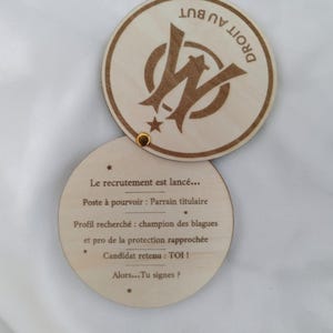 Peut inclure: Ensemble de dessous de verre en bois en deux parties. Le dessous de verre supérieur présente un logo et les mots "DROIT AU BUT". Le dessous de verre inférieur contient du texte en français.