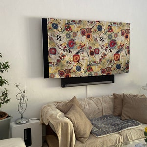 Könnte beinhalten: Ein Wohnzimmer mit einem Sofa, einem Couchtisch, einer Lampe und einem Fernseher mit einer bunten abstrakten Kunstabdeckung.