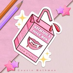 Puede incluir: Una caja de jugo rosa con una boca de vampiro y colmillos. La caja dice "Astarion's Juice Box" y "100% Organic".