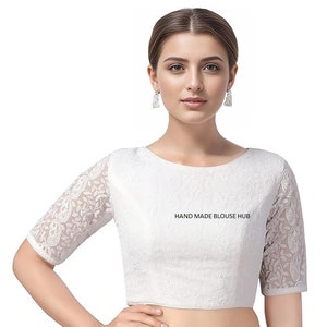 May include: White embroidered blouse with a round neckline and three-quarter sleeves. The blouse has a delicate floral pattern and the text "HAND MADE BLOUSE HUB" is printed on the front.