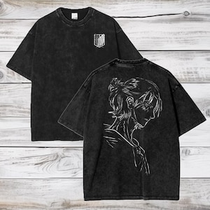 May include: Black t-shirt with a white graphic of a character from the anime Attack on Titan on the back. The front of the shirt has a white graphic of the Attack on Titan logo.