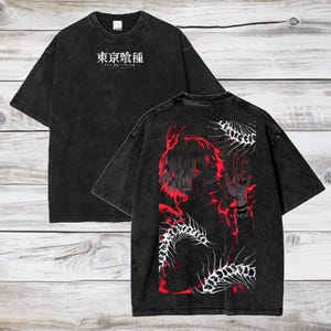 May include: Black t-shirt with Japanese text on the front and a red and black graphic on the back. The graphic features a character with red hair and a hand gesture. The shirt has a vintage wash.