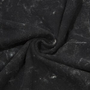May include: Close-up of a black fabric with a white marbled pattern. The fabric is soft and textured.