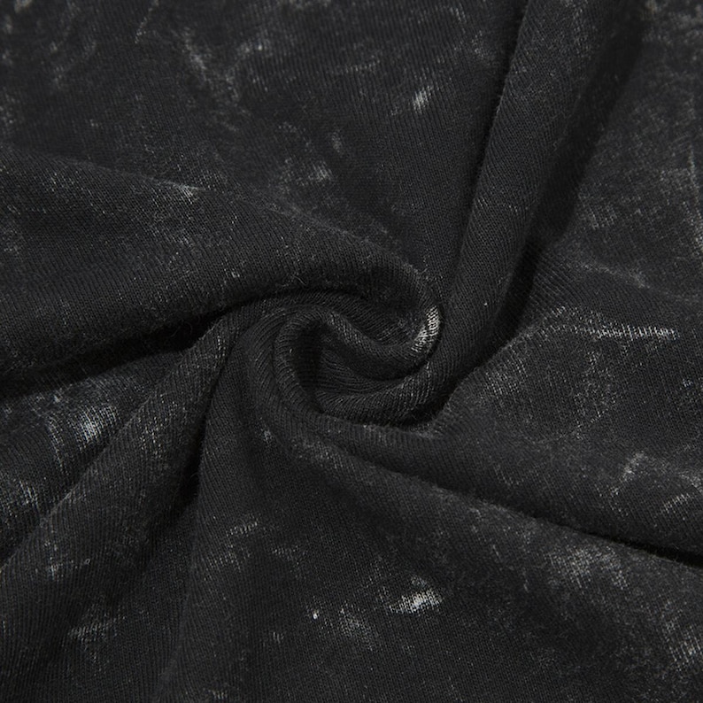 May include: Close-up of a black fabric with a white marbled pattern. The fabric is soft and textured.