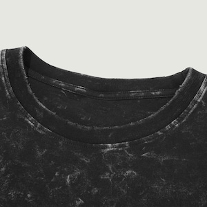 May include: Close-up of the neckline of a black t-shirt with a faded, distressed look.