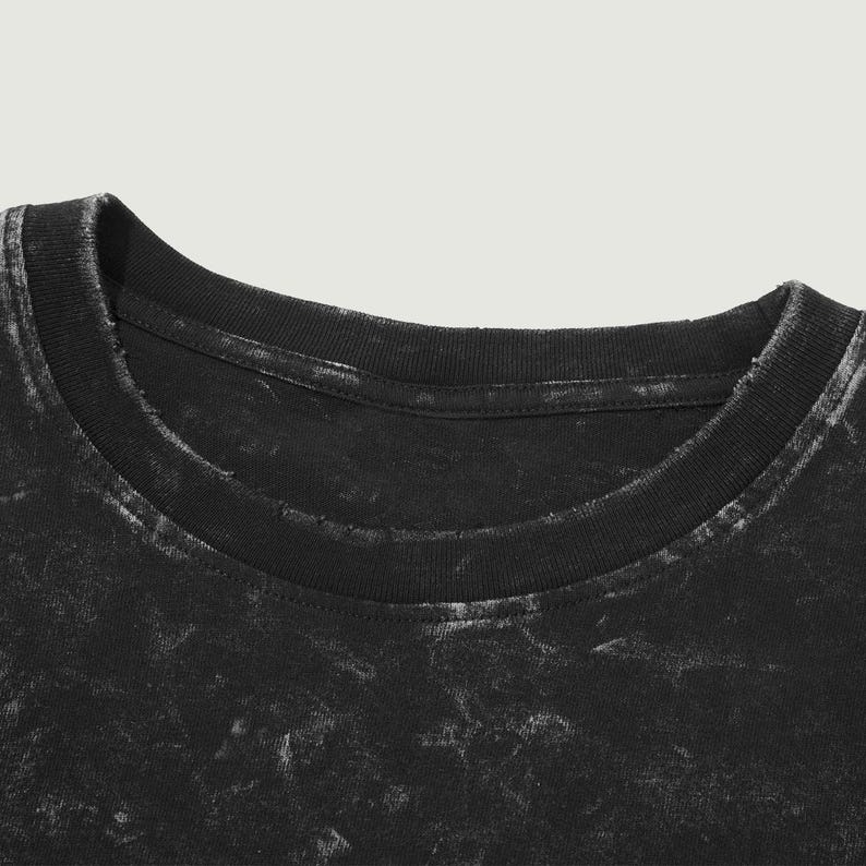 May include: Close-up of the neckline of a black t-shirt with a faded, distressed look.