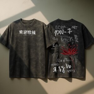 May include: Two charcoal grey t-shirts with short sleeves. One has Japanese text on the front. The other features a red flower illustration and handwritten text in multiple languages on the back. The shirts have a vintage, distressed appearance.