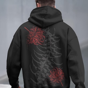 May include: Black hoodie featuring a gray spine and red flower design on the back. The hoodie has a hood and long sleeves. The design includes two red flowers and a spine graphic.