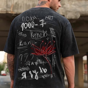 May include: Black t-shirt featuring white handwritten text and a red flower illustration. The text includes numbers, question marks, and foreign words. The shirt has a distressed, vintage appearance.