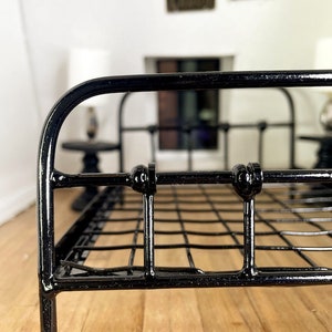 May include: Black metal bed frame with a wire mesh base. The bed frame has rounded edges and decorative accents.