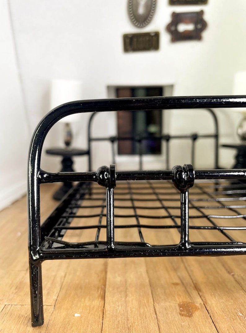 May include: Black metal bed frame with a wire mesh base. The bed frame has rounded edges and decorative accents.