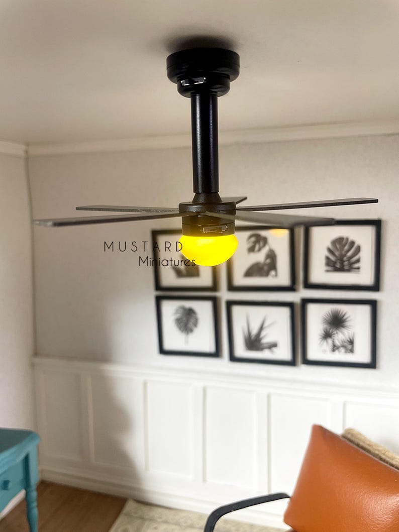 Puede incluir: Ventilador de techo negro en miniatura con seis aspas y luz amarilla. El ventilador est&aacute; montado en un techo blanco. El texto "MUSTARD Miniatures" es visible. Seis grabados bot&aacute;nicos enmarcados cuelgan de la pared.