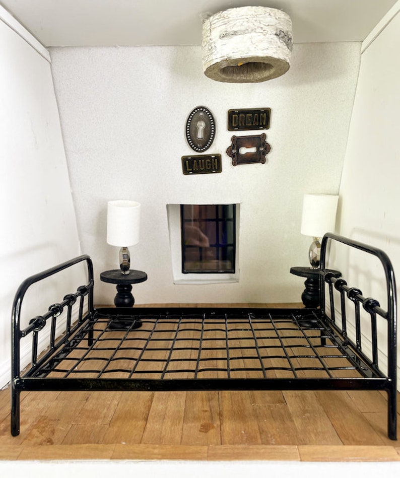 May include: A black metal bed frame with a white ceiling fixture and decorative wall art with the words "Dream", "Laugh", and a keyhole design.