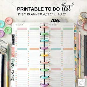 Puede incluir: Un planificador de lista de tareas imprimible, 10,48 cm x 23,50 cm, con casillas de colores pastel y una encuadernación de disco colorida. El planificador presenta el texto "PRINTABLE TO DO list" en la parte superior. Se ven artículos de papelería como lápices y cinta adhesiva.
