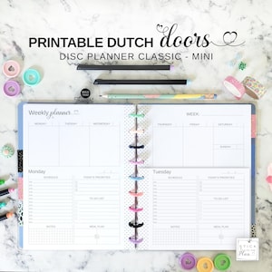 以下が含まれることがあります： 「PRINTABLE DUTCH doors」と「DISC PLANNER CLASSIC - MINI」の文字が入ったディスクプランナー。プランナーは、各曜日、メモ、To-Doリストのセクションがある週ごとのページに開かれています。ペンと装飾テープも表示されています。