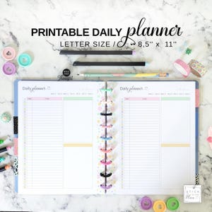 May include: Open daily planner with the text "PRINTABLE DAILY planner" and "LETTER SIZE / 8.5" x 11". The planner is open to a two-page spread with lined sections for tasks. Colorful pens, washi tape, and decorative paper clips surround the planner.