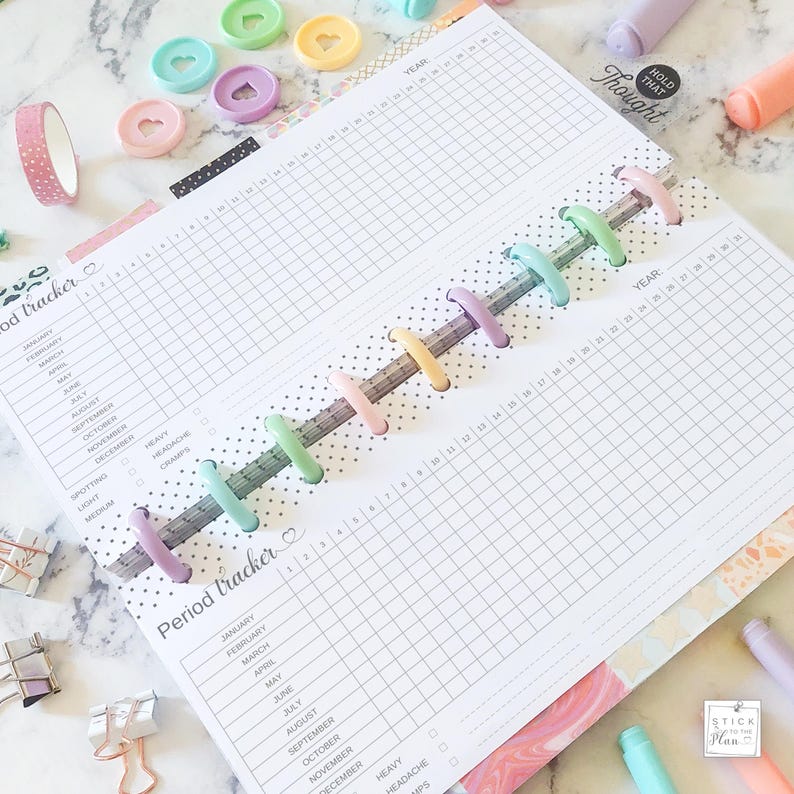 K&ouml;nnte beinhalten: Ein wei&szlig;er Planer mit einem Rastermuster und einem Abschnitt zur Verfolgung der Periode. Der Planer hat ein farbenfrohes Regenbogen-Design und die W&ouml;rter "Period tracker" und "Year" sind auf den Seiten gedruckt.