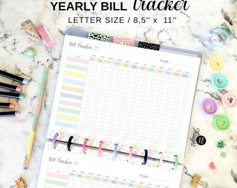 Könnte beinhalten: Ein druckbarer jährlicher Rechnungs-Tracker im Letter-Format von 21,6 cm x 27,9 cm. Das Dokument verfügt über ein Rasterlayout mit Spalten für Monate und Zeilen für Posten, akzentuiert mit Pastellfarben. Es ist mit bunten Kunststoffscheiben gebunden und von Schreibwaren wie Washi-Tape, Stiften und kleinen Büroklammern umgeben.