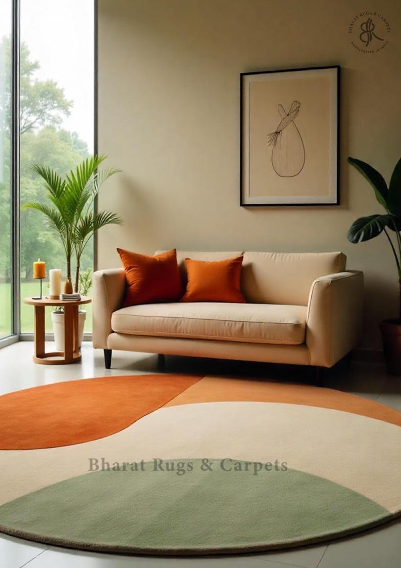 Puede incluir: Una alfombra redonda multicolor con un esquema de color verde, crema, naranja y &oacute;xido. La alfombra est&aacute; en un sal&oacute;n con un sof&aacute; blanco y almohadas naranjas. El texto "Bharat Rugs & Carpets" es visible en la alfombra.
