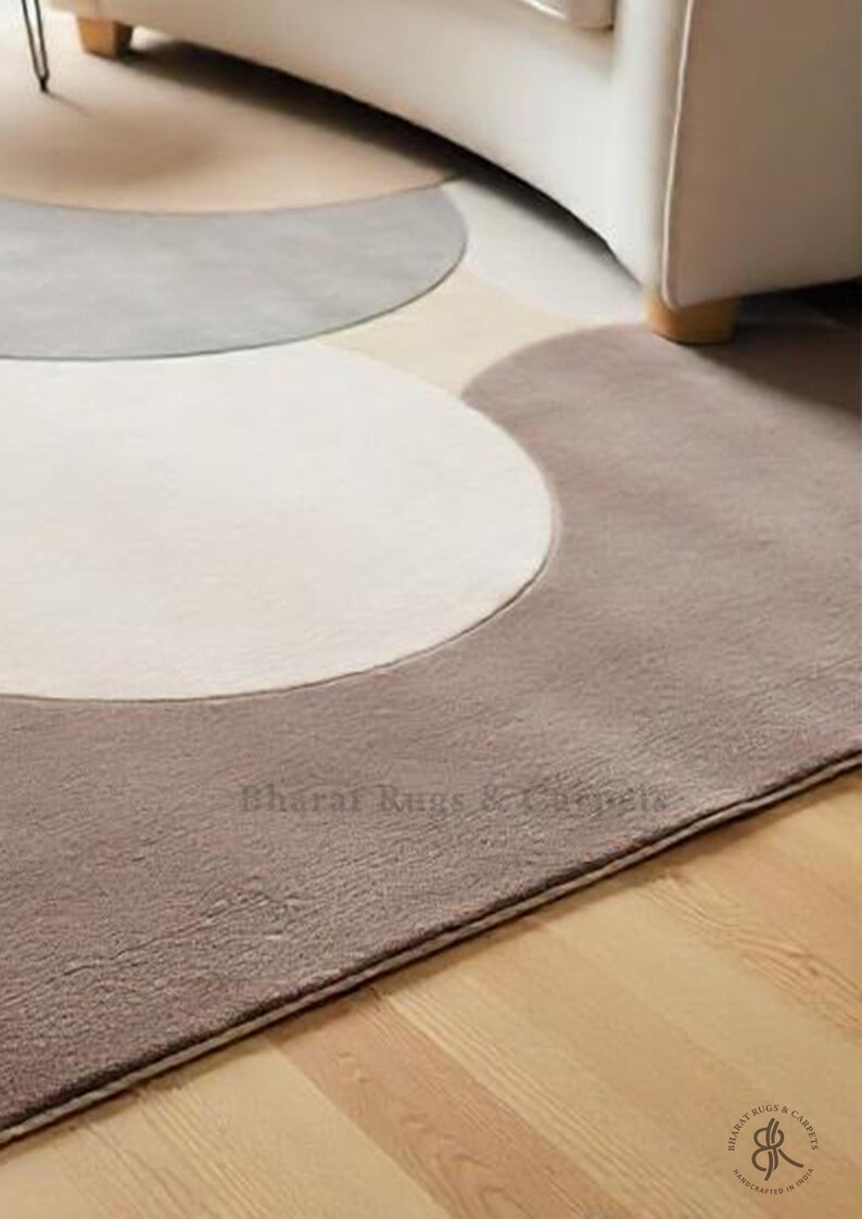 May include: A modern abstract rug with a design of overlapping circles in shades of beige, gray, and brown. The rug has a soft, plush texture and a subtle sheen.